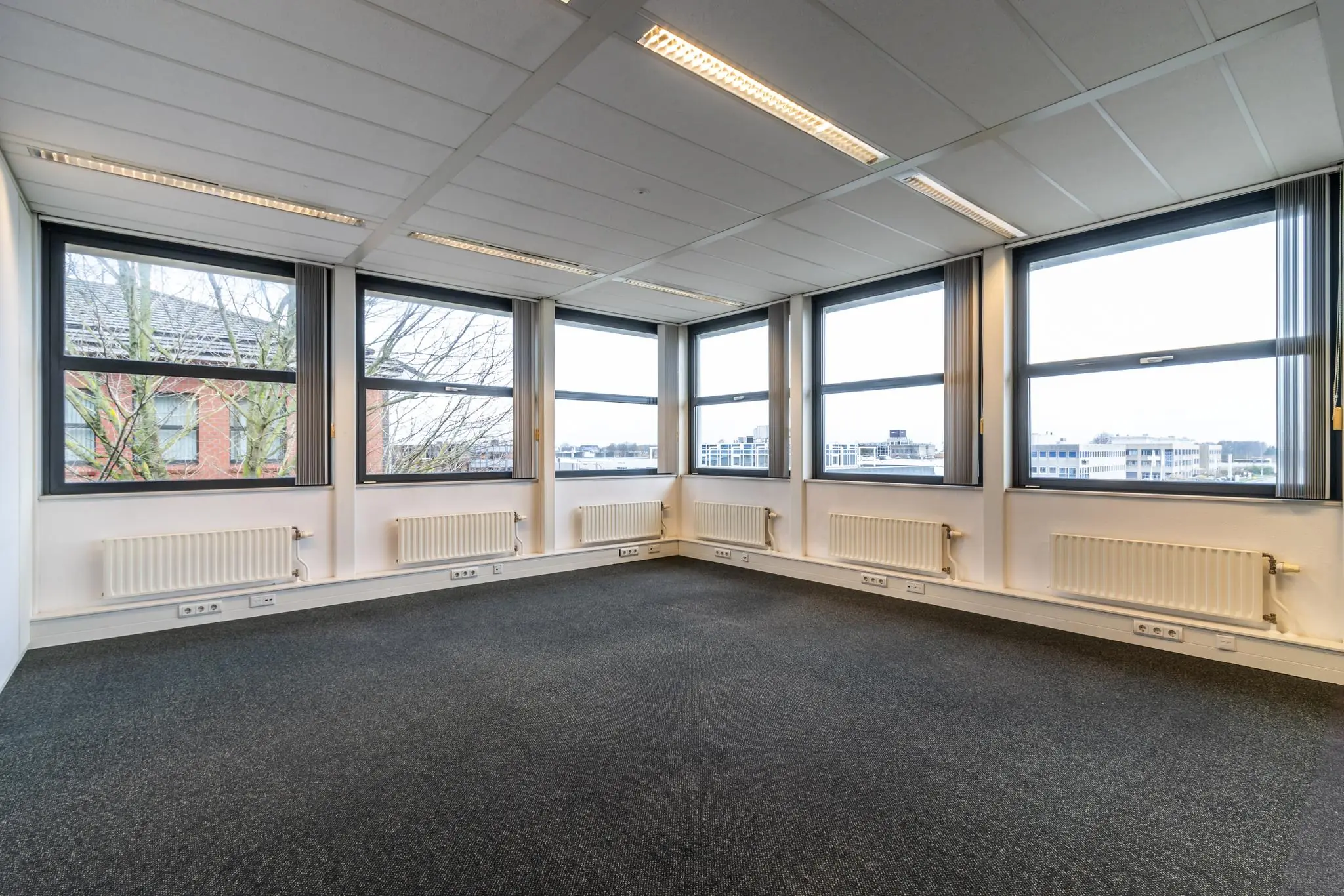 Licht en leeg kantoorkantoor aan de Lange Dreef met grote ramen en donker tapijt.